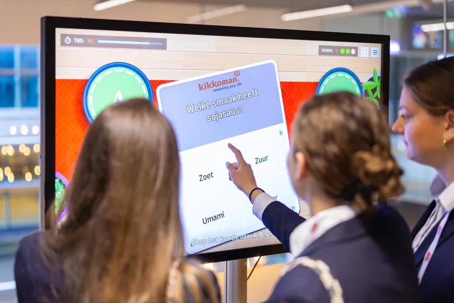 Studenten spelen een CuliQuiz-vraag van Kikkoman op een groot touchscreen